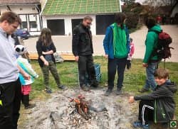 Skupina lidí opéká buřty na ohni