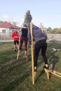Dvě ženy na chůdách, v pozadí muž a strom