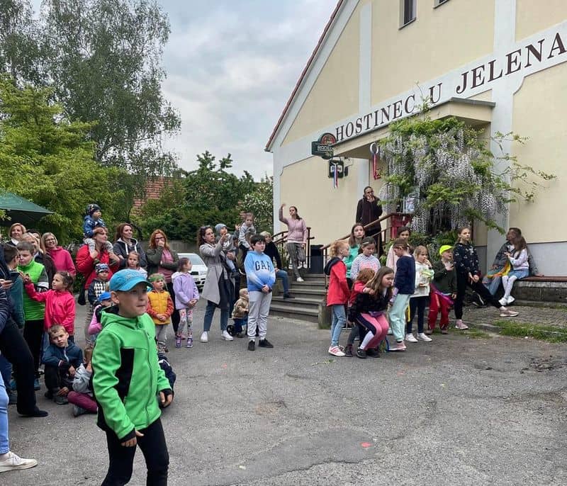 Skupina dětí a dospělých před hostincem U Jelena