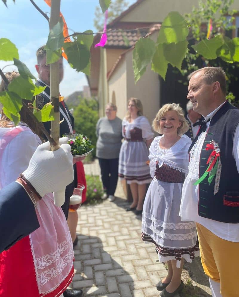 Skupina lidí v krojích a muž s májkou