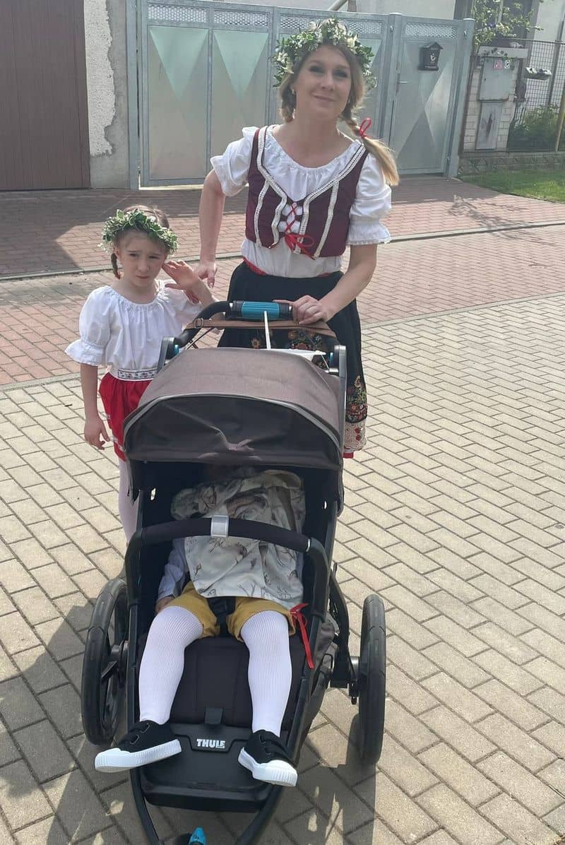 Žena a dvě děti v krojích, jedno v kočárku