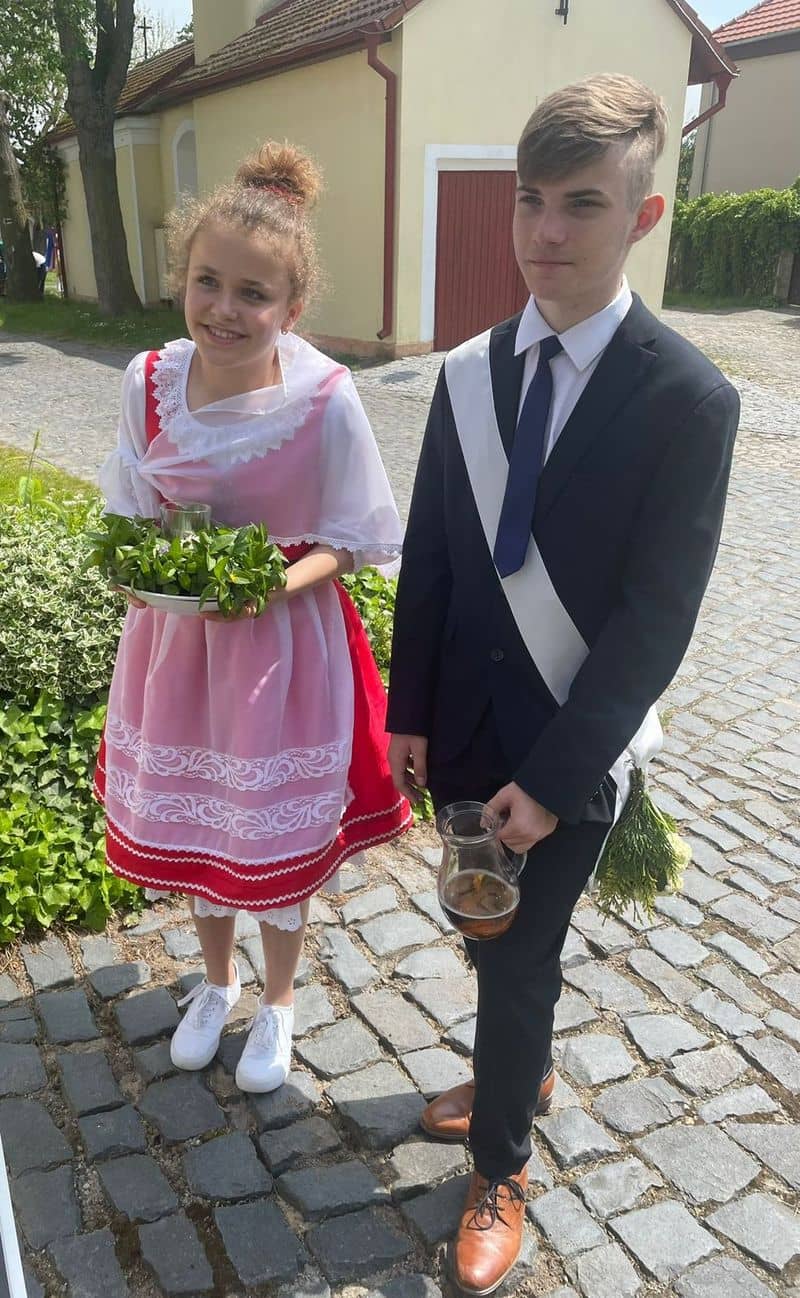 Dívka v kroji s tácem a chlapec v obleku s džbánem a kyticí