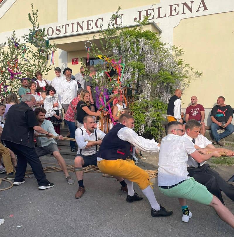 Skupina mužů přetahuje lano před Hostincem U Jelena