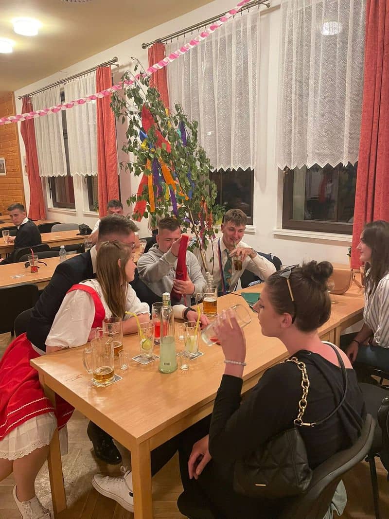 Skupina lidí u stolu s nápoji a ozdobenou břízou