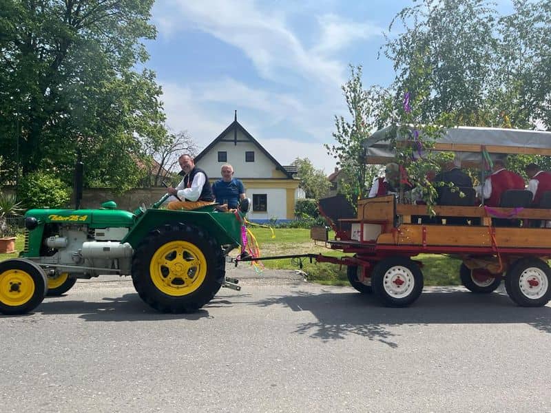 Zelený traktor Zetor 25 A táhne vůz s lidmi v krojích
