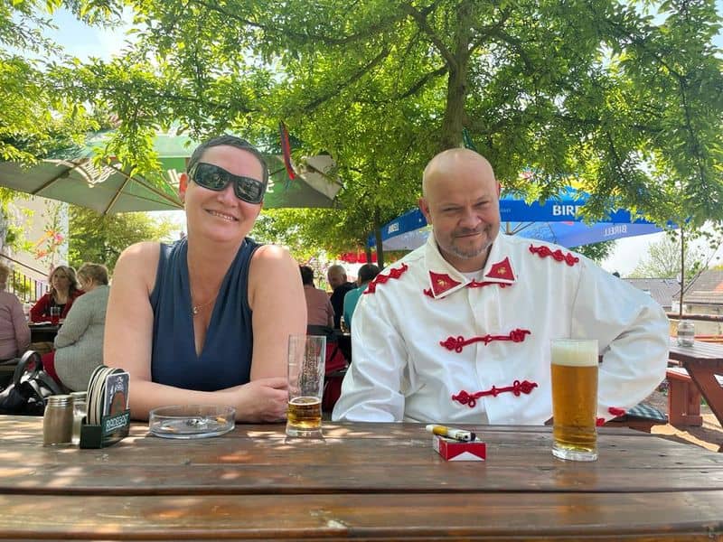 Žena a muž v kroji sedí u stolu s pivem