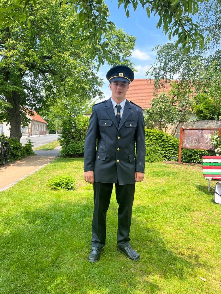 Mladý muž v uniformě stojí na trávníku