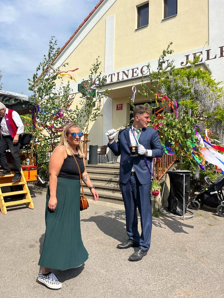 Žena a muž v obleku před budovou s nápisem Hostinec