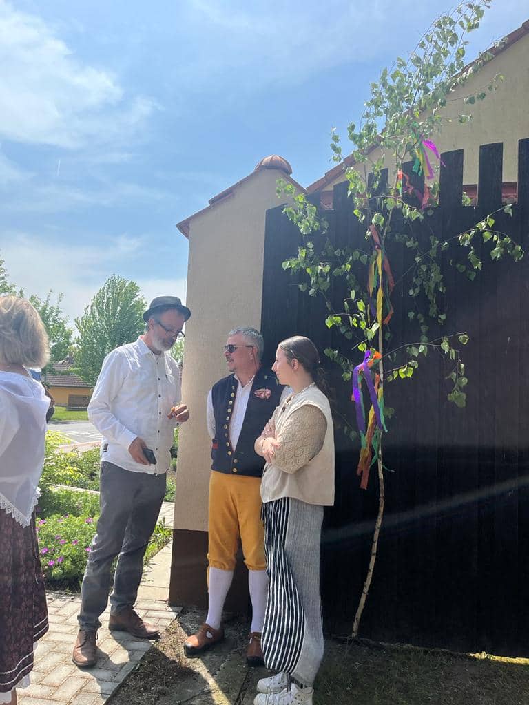 Skupina lidí u májky s barevnými stuhami