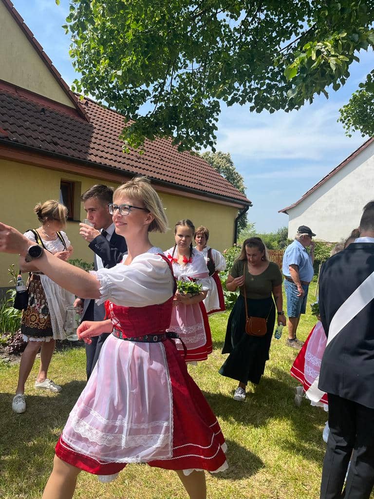 Skupina lidí v krojích a oblecích na zahradě