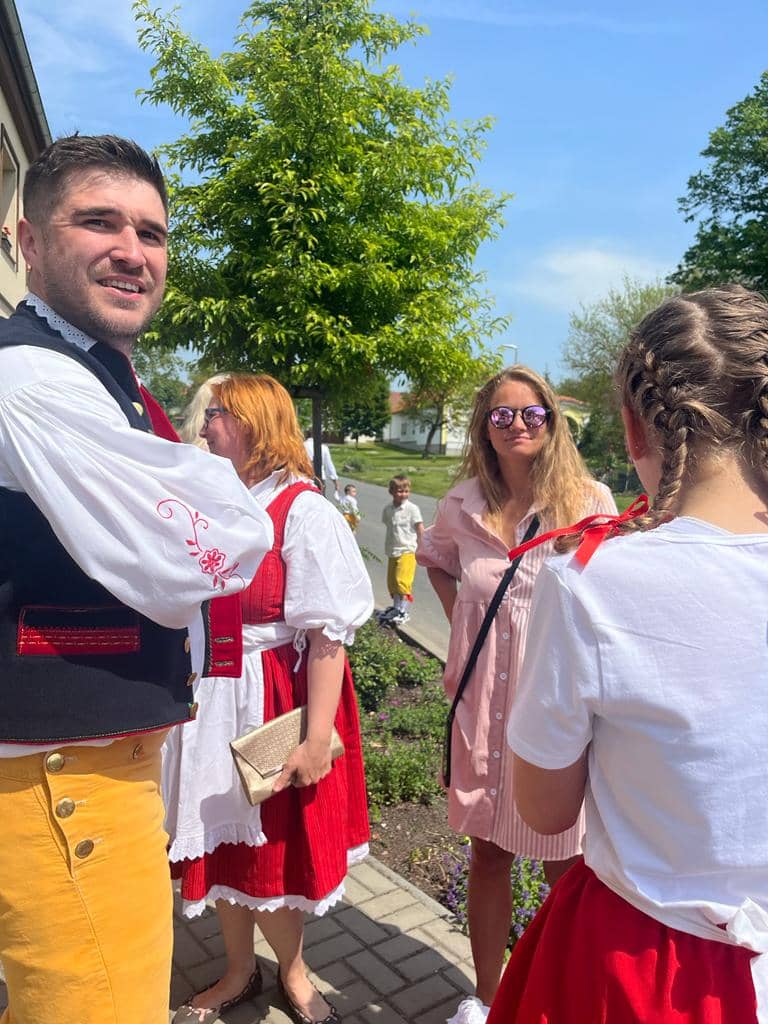 Skupina lidí v krojích a letním oblečení na ulici